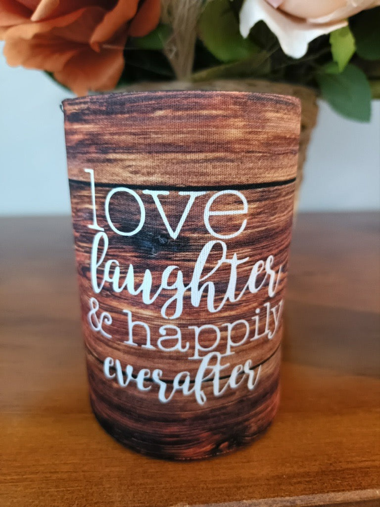 Wooden container with 'love laughter & happily everafter' text on a wooden surface with flowers in the background.